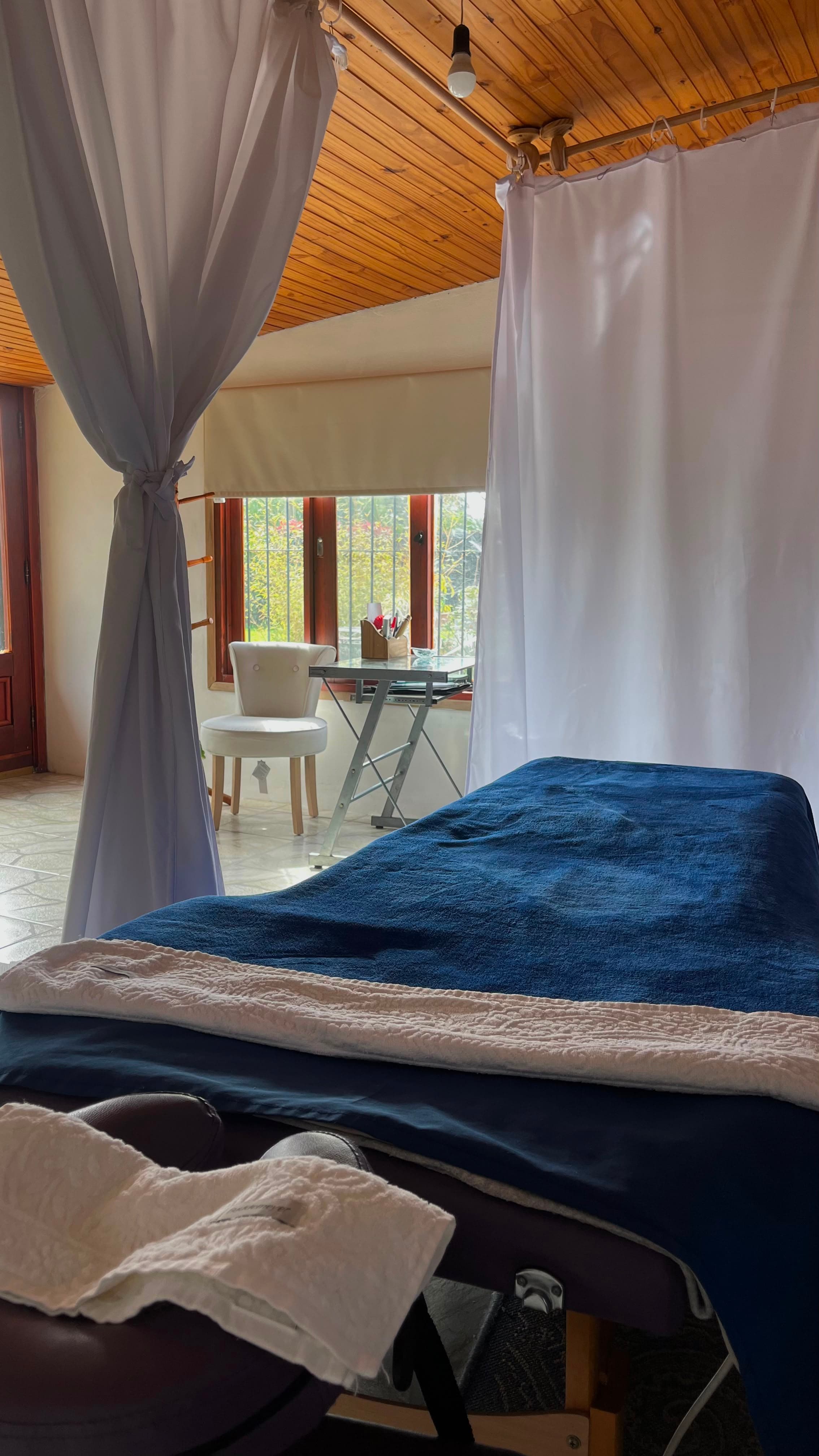Camilla de masajes SentirSe con cortinas blancas y luz natural